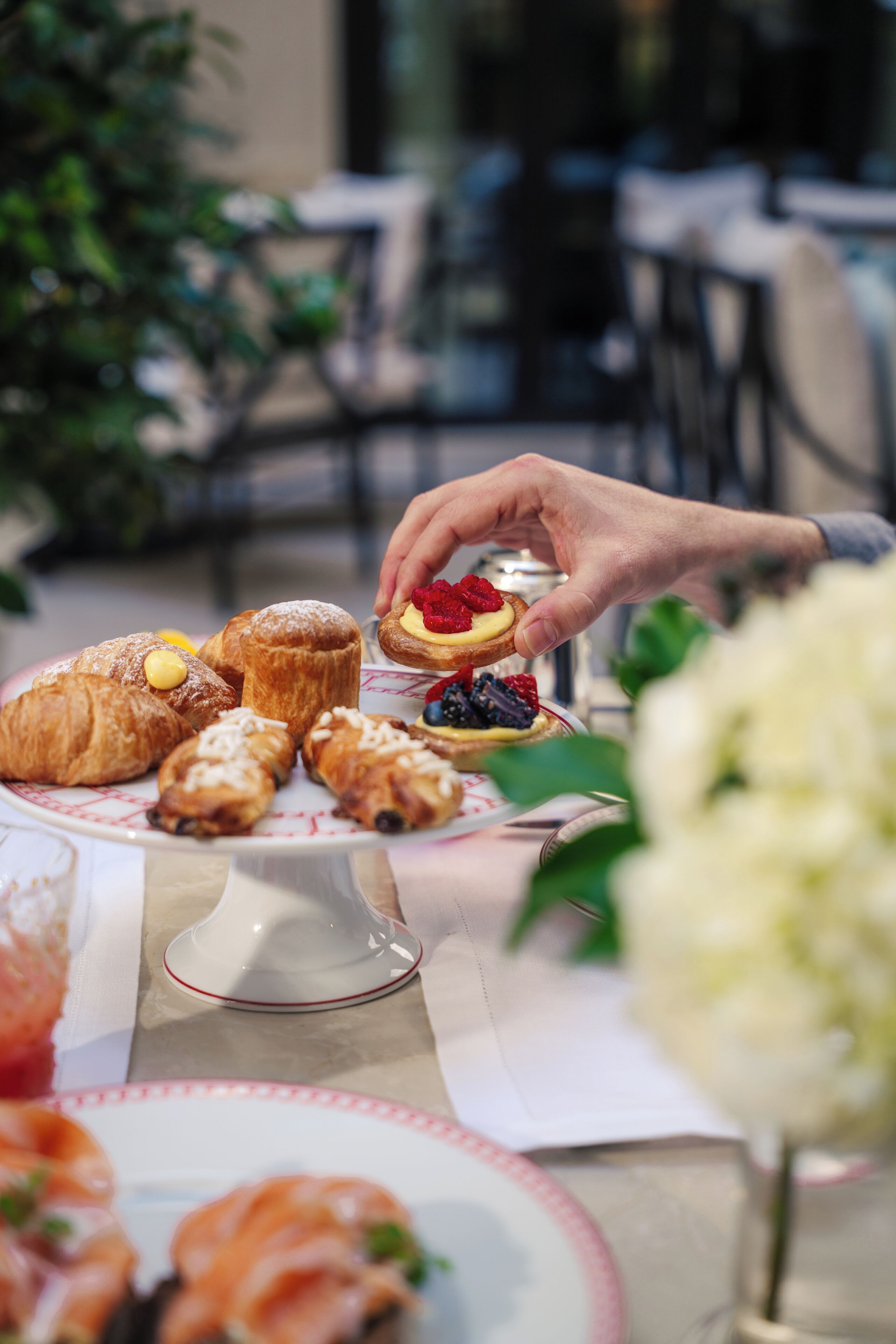 Una mesa con pasteles y una mano alcanzando uno.