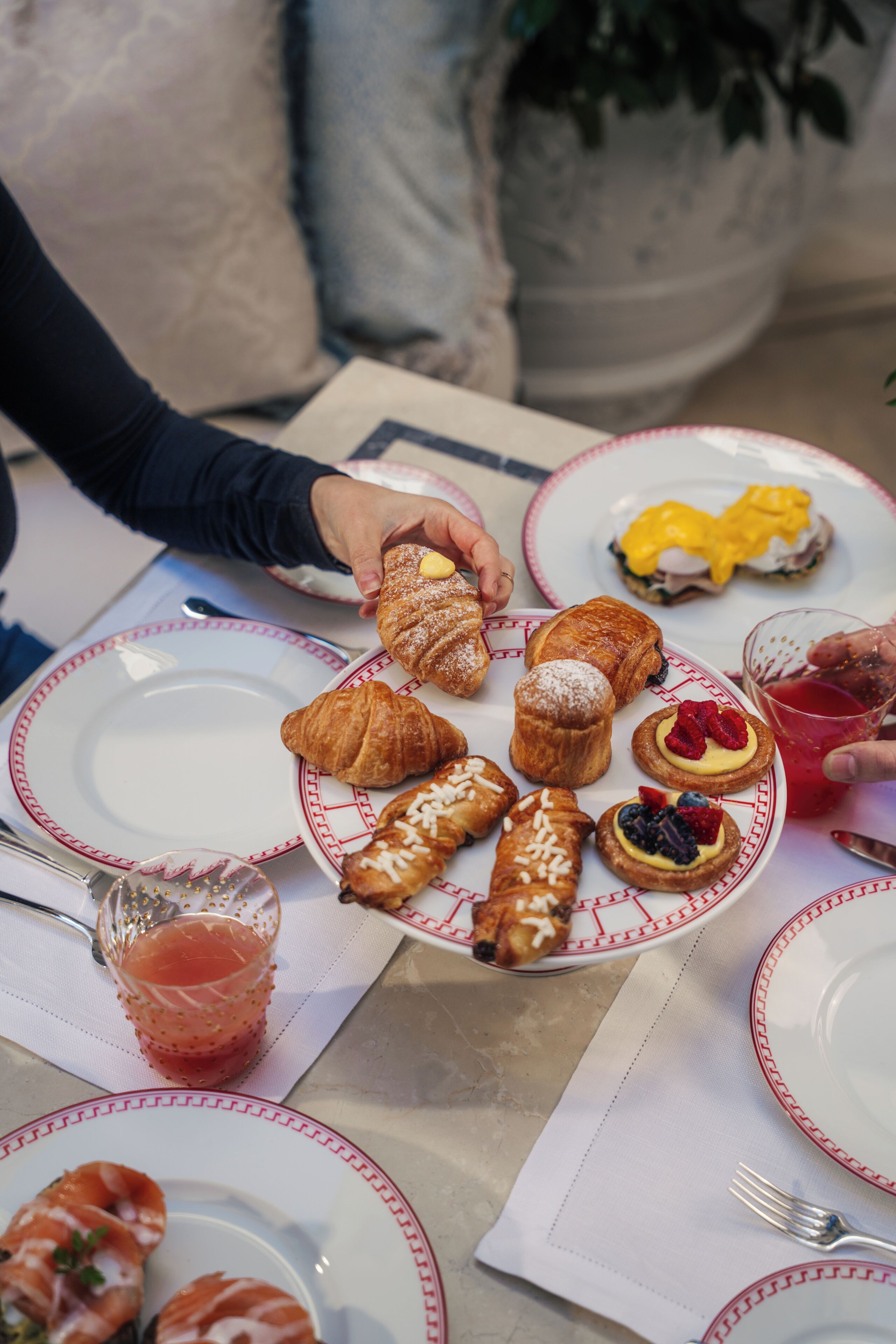 A table with plates of pastries and a glass of drink.