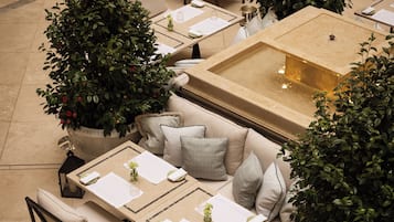 An outdoor dining area with tables, chairs, and potted plants.