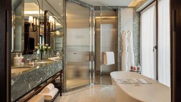 A modern bathroom with a marble vanity, a glass shower enclosure, and a freestanding bathtub.