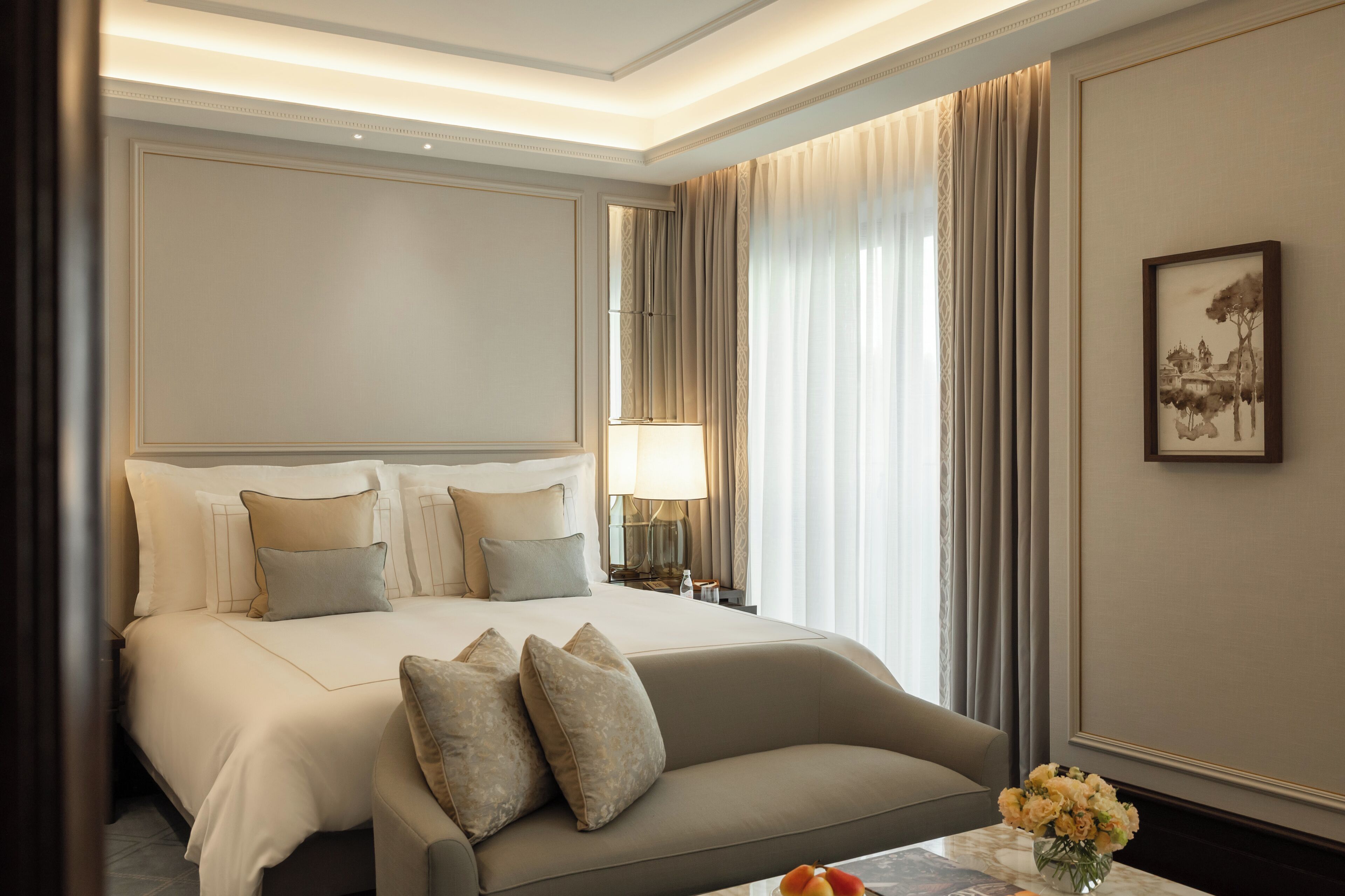 Una habitación de hotel con una cama grande, un sofá, una mesita de noche con lámpara y un cuadro enmarcado en la pared.