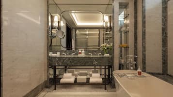 A modern bathroom with a marble vanity, a large mirror, a bathtub, and a glass shower enclosure.