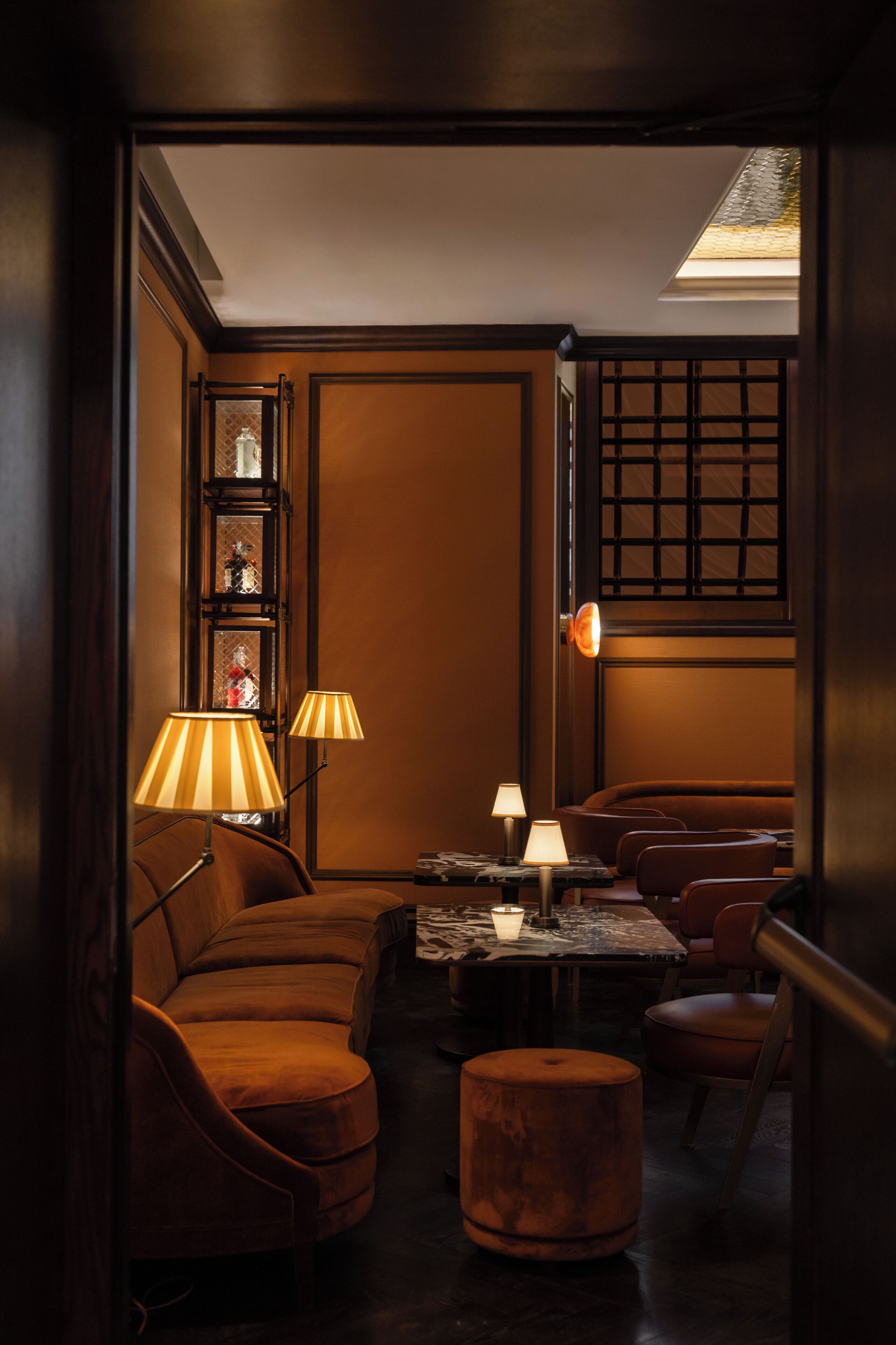 Een kamer met gedimd licht, een bank, een voetenbankje en twee lampen.