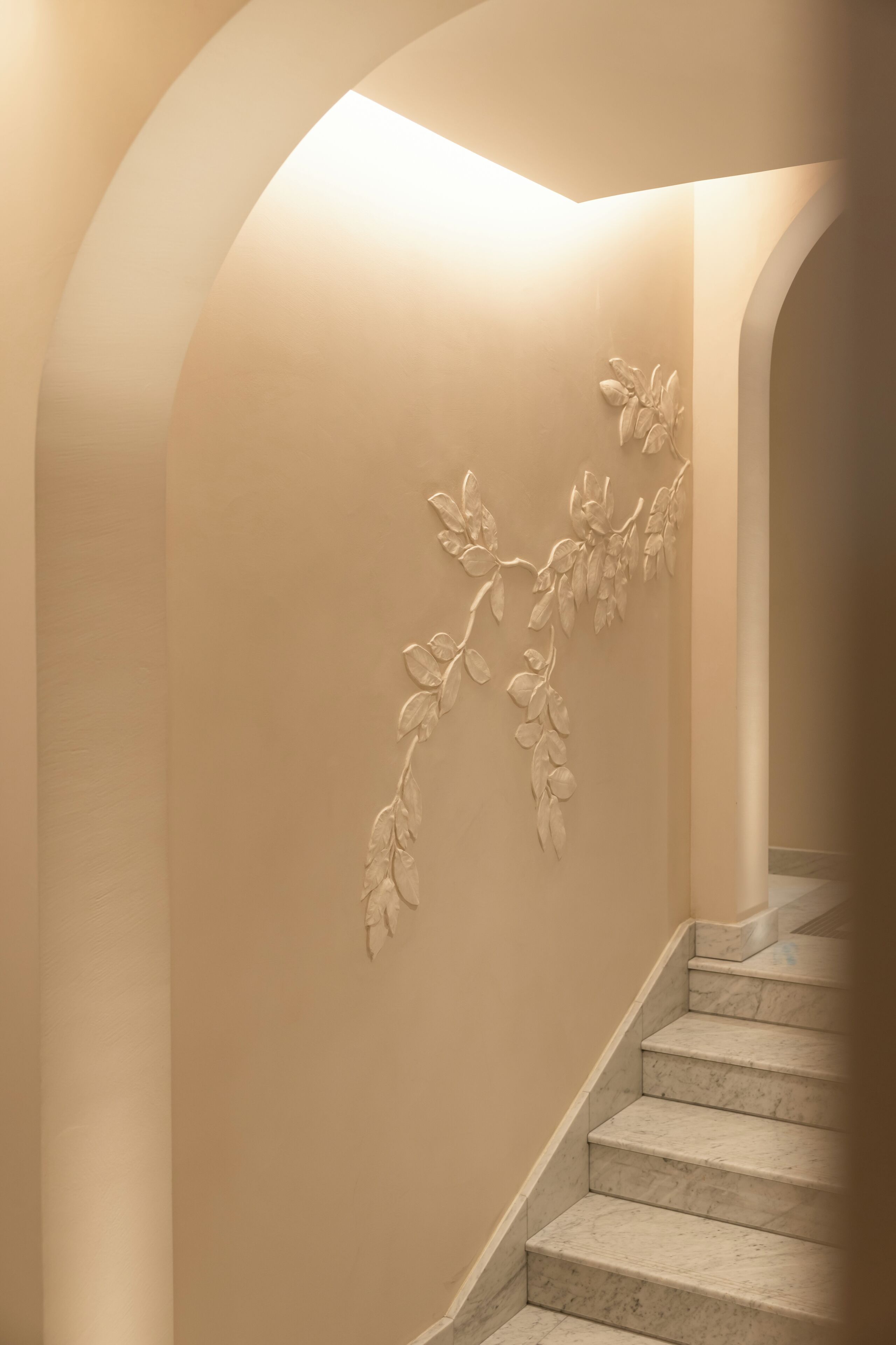 A staircase with a beige wall and a floral wall decoration.