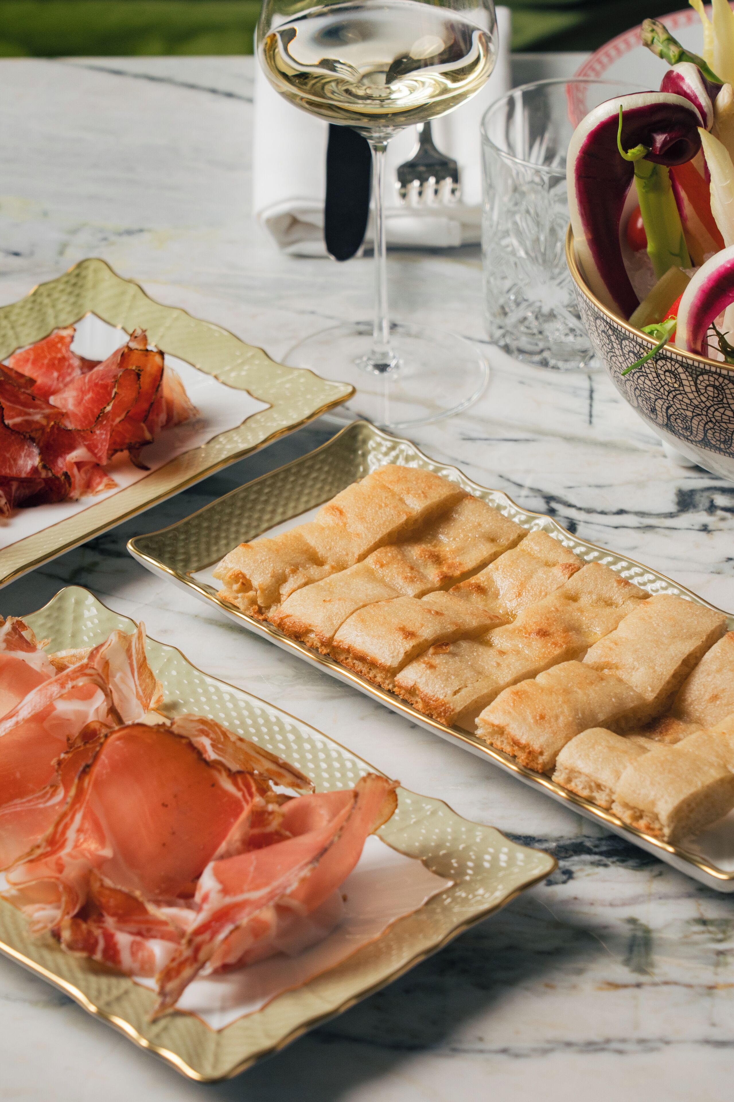 A marble table with food items and a wine glass.