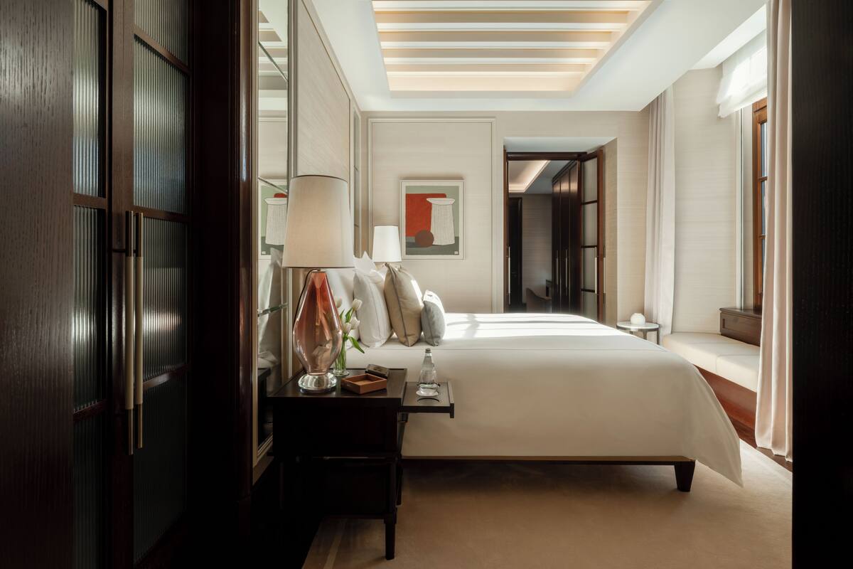 A hotel room with a large bed, bedside tables, a lamp, and a framed artwork on the wall.