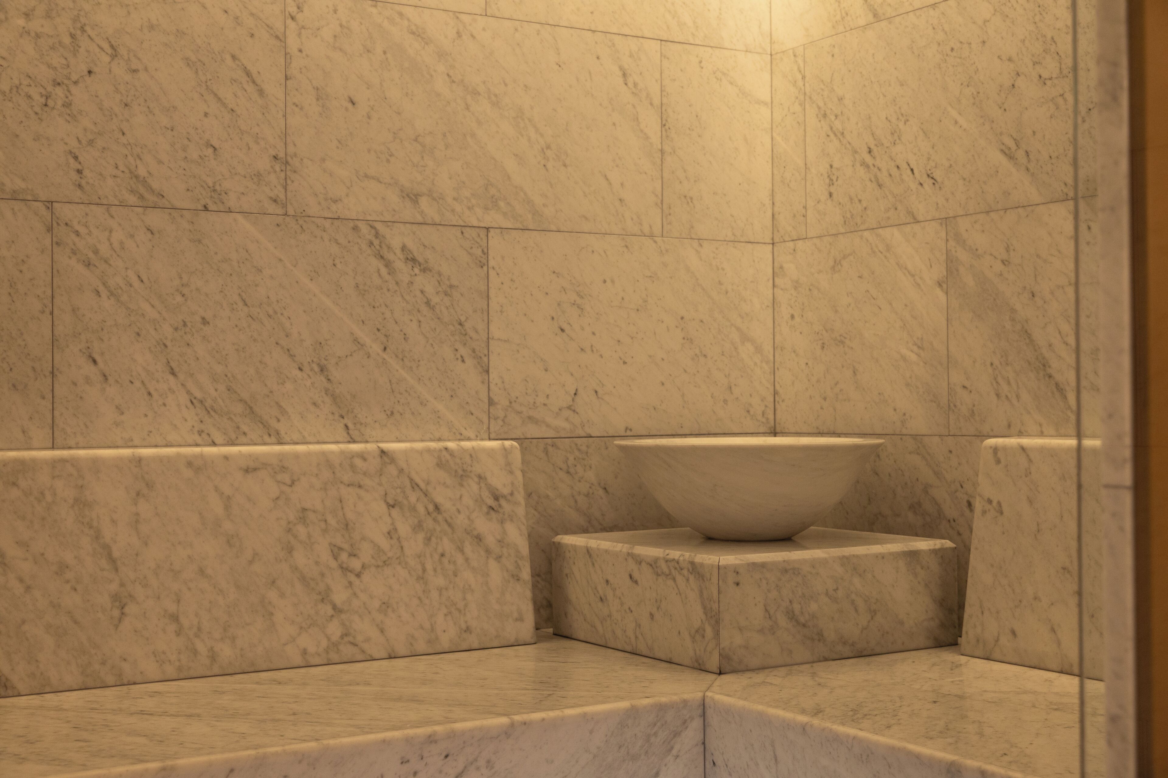 Un baño con paredes de mármol y un lavamanos grande.