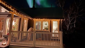 A house with a porch and a chimney, under a night sky with the aurora borealis. - Cottage for Rent by the sea (Narvik)