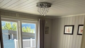 A bedroom with a bed, a window, a chandelier, and a door. - Cottage for Rent by the sea (Narvik)