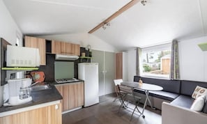 Uma cozinha compacta com área de refeições, forno embutido e janela com cortinas.