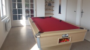 Une table de billard recouverte d’un feutre rouge, un tiroir contenant les billes et une porte portant le numéro « 2 ».