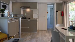Eine kleine Küche mit Herd, Spüle und Schränken, die in einen Essbereich mit Tisch und Stühlen übergeht.