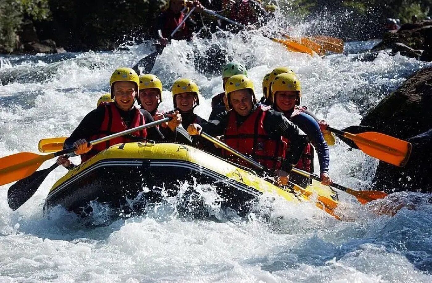 A group of people in a yellow raft navigating through rapids.