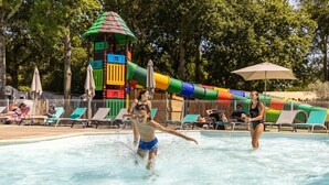 A swimming pool with a colorful play structure in the background and lounge chairs along the poolside. - ZEcamping 4* 4km plage parc aquatique fitness dog friendly club enfant (Saint-Sulpice-de-Royan)
