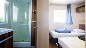 Une chambre à coucher avec un lit, une fenêtre avec des rideaux et un espace douche doté d’une porte en verre.