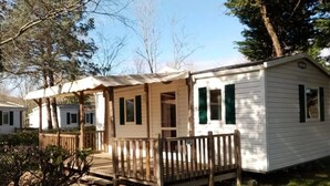 Une maison mobile dotée d’un porche et d’une terrasse délimitée par une clôture.