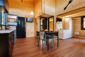 Ein Holzblockhaus-Innenraum mit Küche, Essbereich und einem großen Fenster.