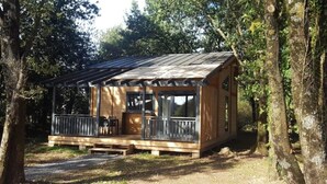 A wooden cabin with a porch, surrounded by trees. - ZEcamping 4* animé piscine couverte locatif TV LV (Caro)