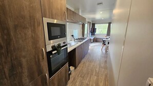 Una cucina moderna con elettrodomestici in acciaio inox, mobili in legno e vista sull'area pranzo.