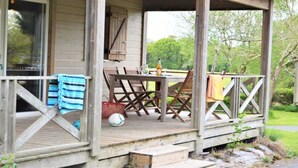 Une terrasse en bois avec une table et des chaises, une bouteille et un panier.