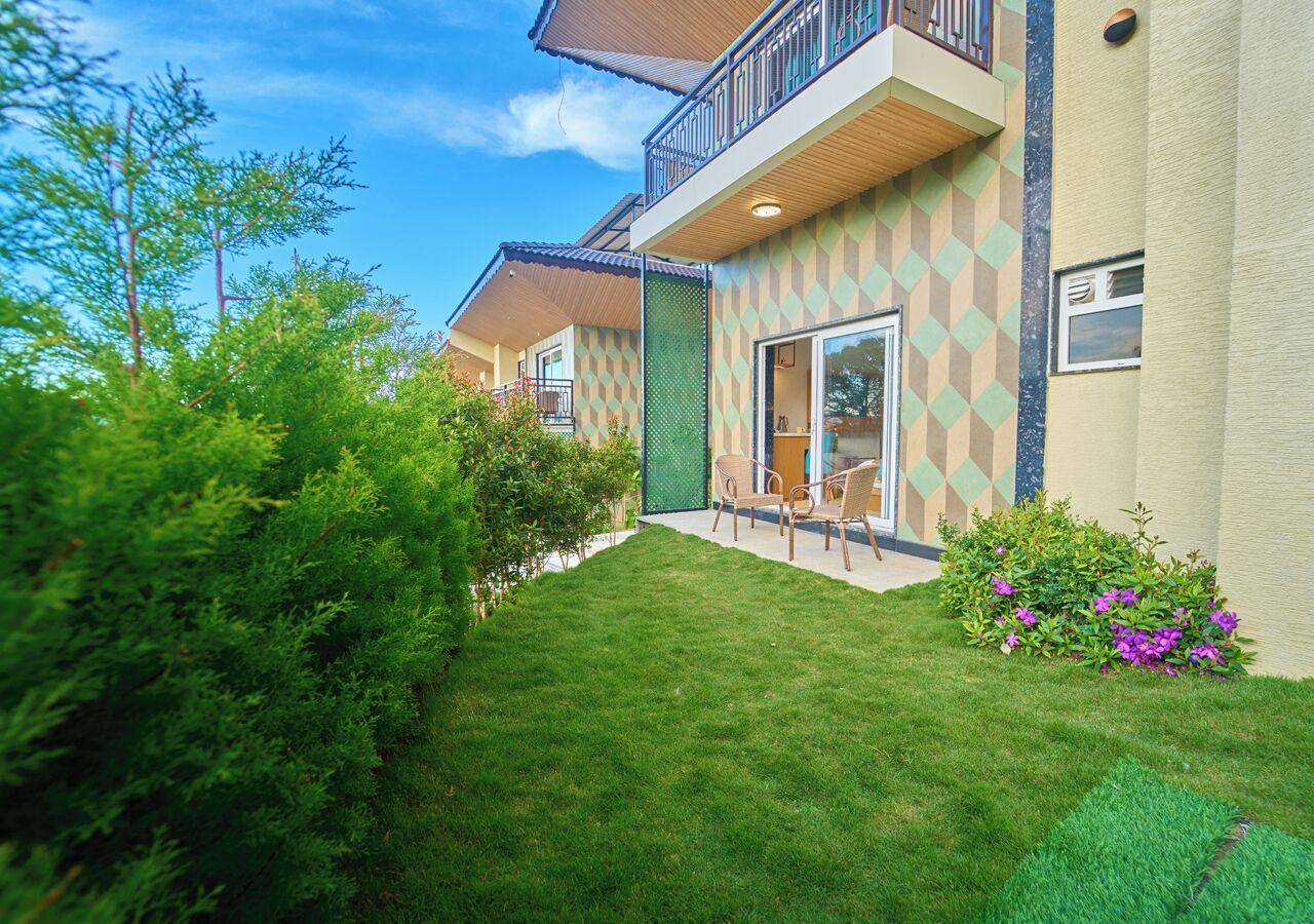 A modern building with a geometric facade, a well-maintained lawn, and outdoor seating.