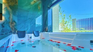 A spa room with a large bathtub filled with water and rose petals, a window with a view of greenery, and a marble wall. - Cloudskape Resort Ooty by VOYE HOMES (Ooty)