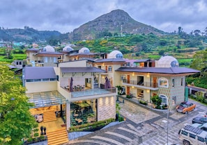 A modern hotel with multiple dome-roofed buildings, a central courtyard, and a mountainous backdrop. - Cloudskape Resort Ooty by VOYE HOMES (Ooty)