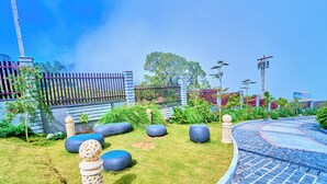 A landscaped garden with a curved stone pathway, decorative bollards, and a fence. - Cloudskape Resort Ooty by VOYE HOMES (Ooty)