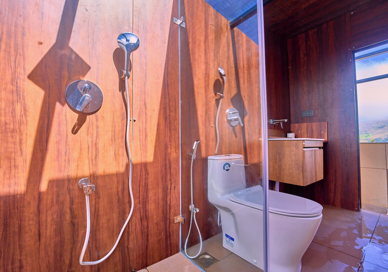 A bathroom with a wooden vanity, a toilet, and a shower with a glass enclosure.