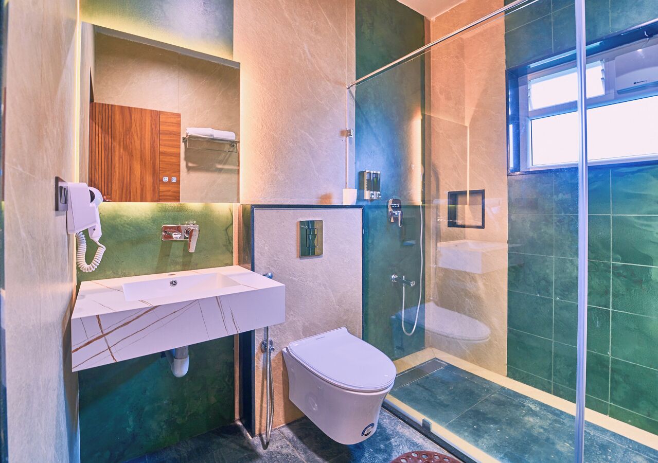 Un baño moderno con cabina de ducha de vidrio, un lavamanos blanco y un inodoro.