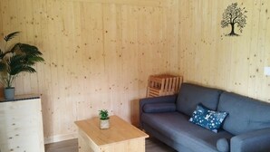 A cozy room with a wooden floor, a blue sofa, a small wooden table, and a potted plant.