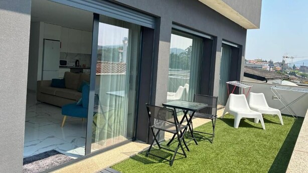 A modern apartment with a balcony, a dining area, and a view of the cityscape. - In Barcelos View Lodge (Barcelos)
