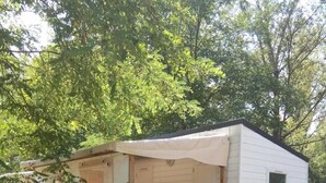 En mindre, etetages campingvogn med en overdækket veranda og en skydedør.
