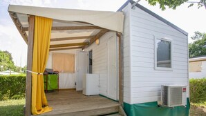 En campingvogn med træterrasse, lille tekøkken og et vindue.