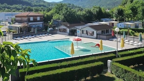 Et hotel med swimmingpool, liggestole og udsigt til de omkringliggende bakker.