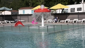 A swimming pool with a water fountain, lounge chairs, and umbrellas. - ZEcamping 4* pataugeoire animaux acceptés cottage TV LV clim 32m2 (Foix)