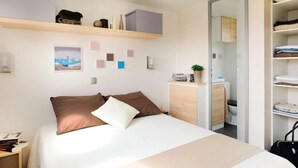 Une chambre bien rangée, avec un lit, des tables de chevet, une armoire et un bureau avec une chaise.