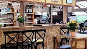 Eine Bar mit einer Steintheke, schwarzen Stühlen und einem Holztisch mit gelben Blumen.