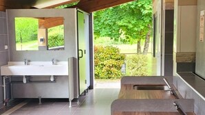 A modern kitchen with a wooden countertop, a sink, and a view of a garden. - ZEcamping 3* pataugeoire piscine dog friendly locatif TV clim 26m2 (Les Assions)