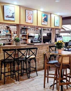 A bar area with a stone counter, black chairs, and a wooden table with yellow flowers. - ZEcamping 3* pataugeoire piscine pet friendly locatif TV clim 31m2 (Les Assions)