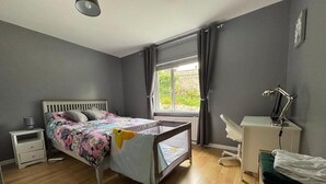 A bedroom with a bed, bedside table, desk, chair, and a window with curtains. - Christinas Cottage - Family- Garden-wifi-sleeps 6 (Downpatrick)