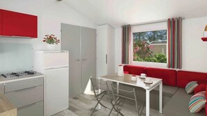 Een kleine keuken met een kookplaat, koelkast en een eethoek met een tafel en stoelen.