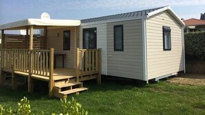 Een gelijkvloerse stacaravan met een overdekte veranda en een klein terras.