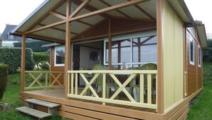Une terrasse en bois avec une rambarde, une table et des chaises.
