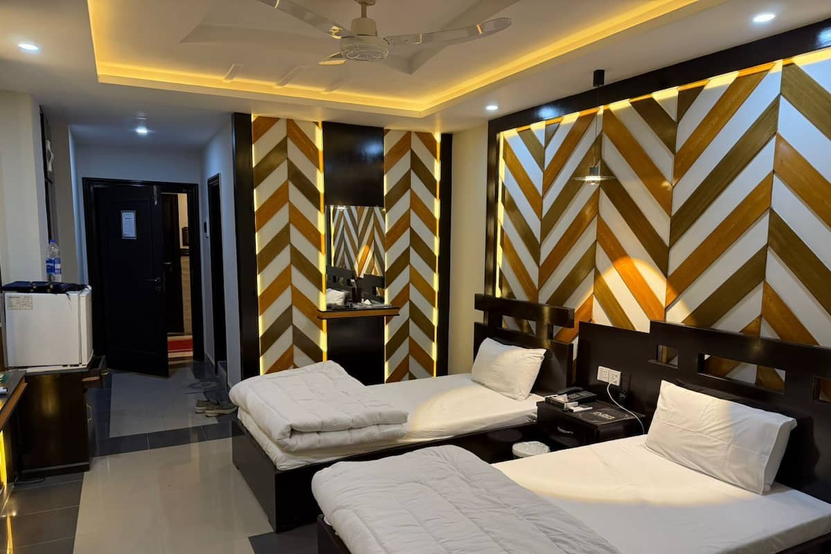A modern hotel room with two beds, a desk, and a mirror.
