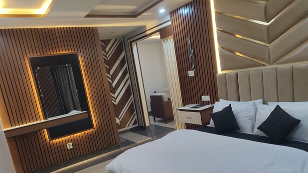 A modern hotel room with a large bed, a desk, and a mirror. - Sapphire Stays Peshawar  (Peshawar)