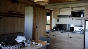 A compact kitchen with wooden cabinetry, a microwave, a coffee maker, and a sink. - ZEcamping 4 étoiles familial 200m plage piscine couverte tente TV LV (Plomodiern)