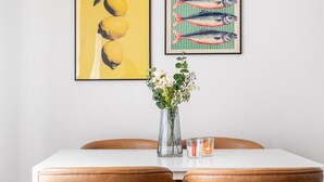 A dining area with a white table, two brown chairs, a vase with flowers, and two framed artworks on the wall. - Garibaldi - Modern 1 BR in Brera by Rentopolis (Milan)