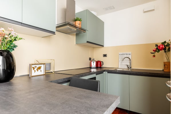 A modern kitchen with a central island, a built-in oven, and a range hood. - Garibaldi - Bright Cozy 1 BR in the Heart of Brera (Milan)
