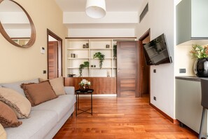 A modern living room with a sofa, a coffee table, and a TV mounted on the wall. - Garibaldi - Bright Cozy 1 BR in the Heart of Brera (Milan)